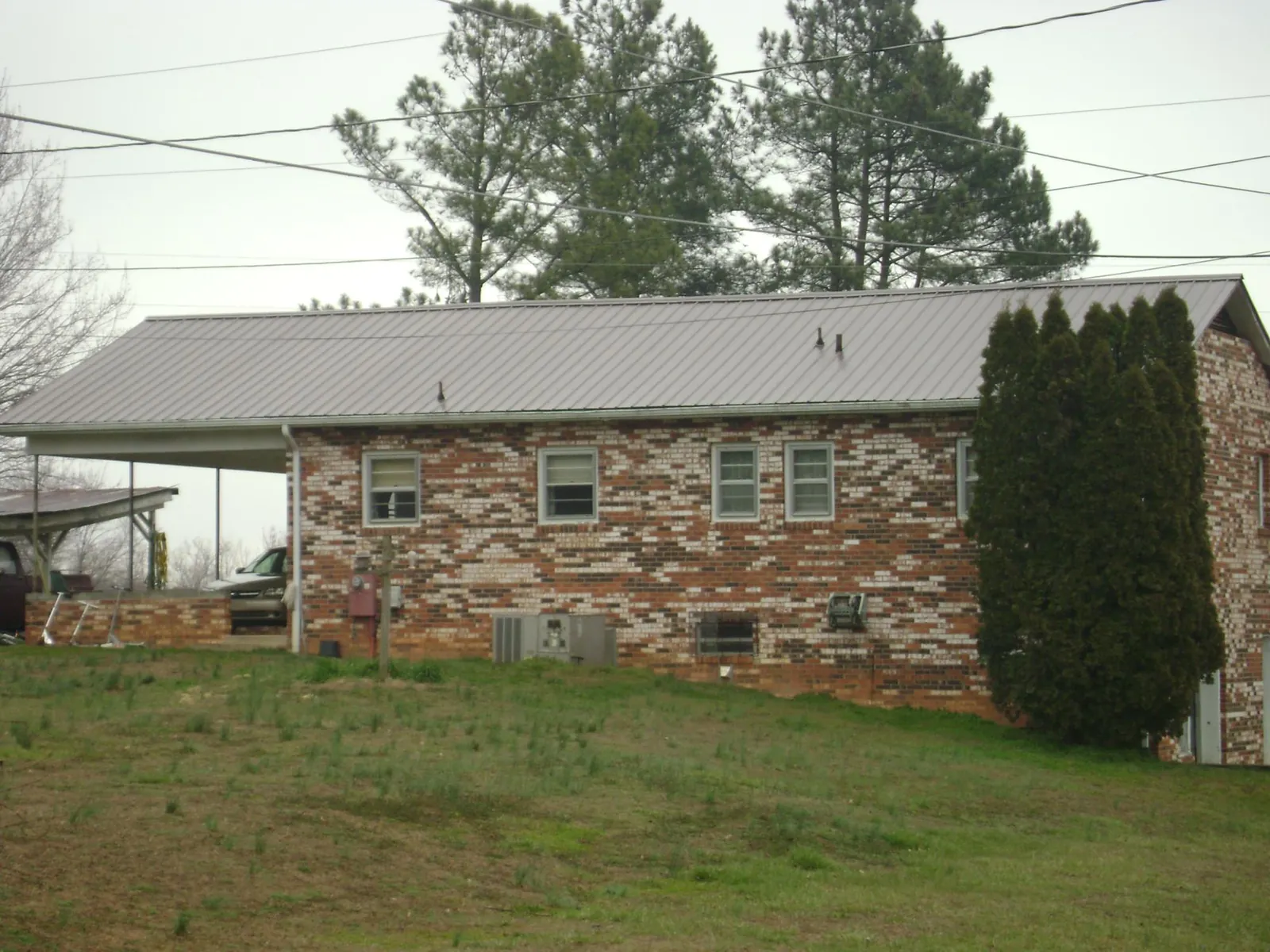 Gray metal roof on a brick split level home with a carport in Alto